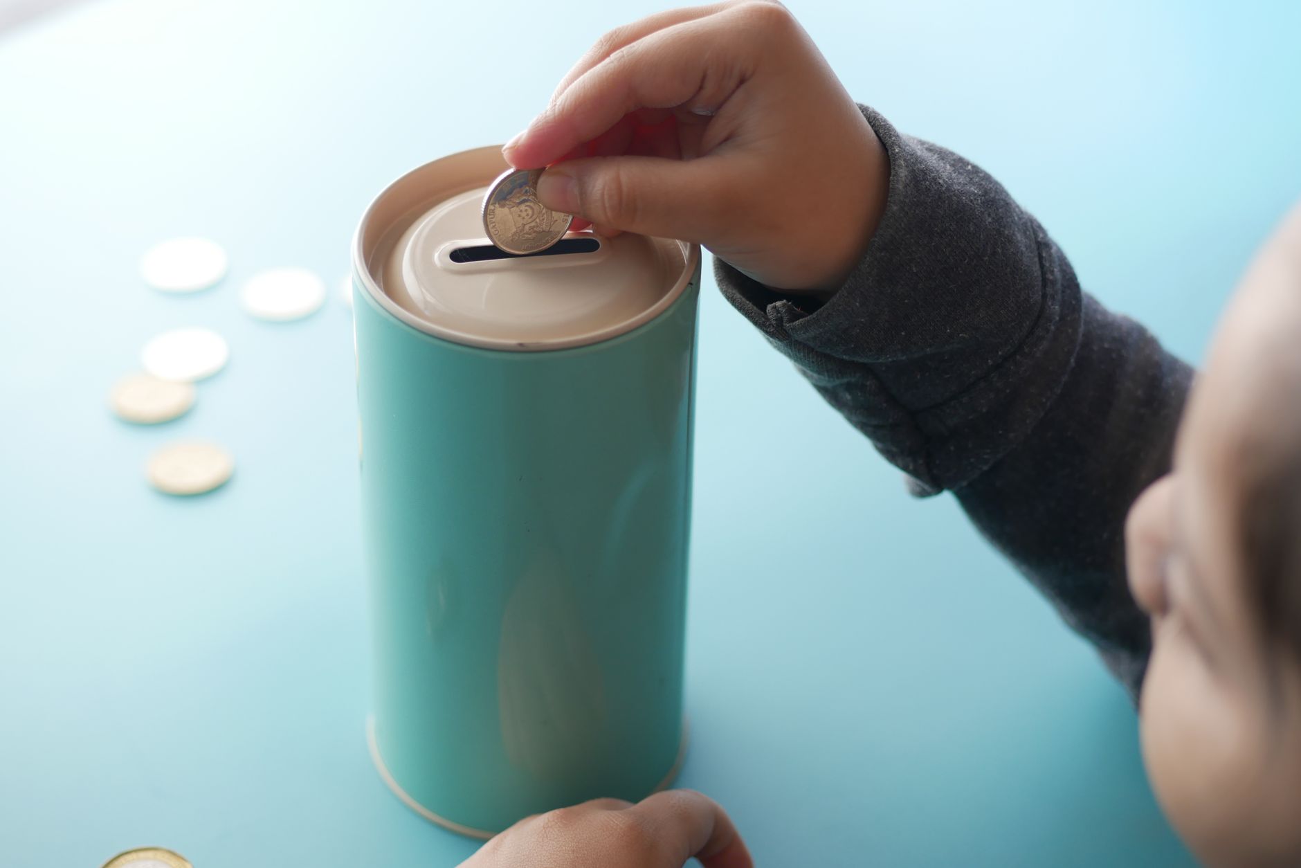 Child placing coin into piggy bank — children's checking account guide