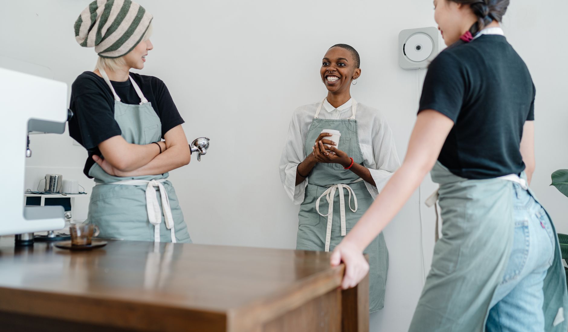 Cheerful young woman in apron smiling at work in a coffee shop — first job money tips for teens