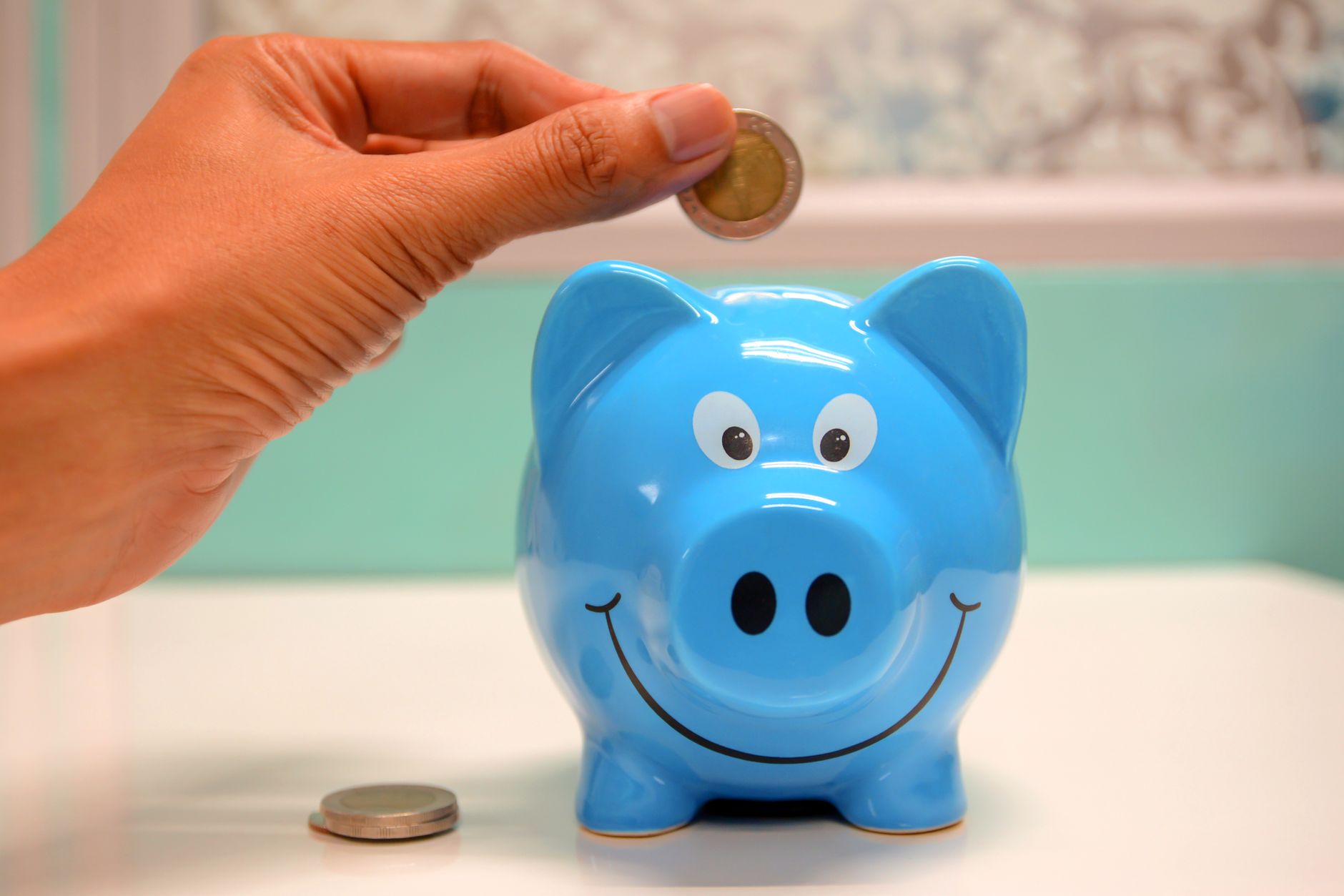 Child placing a coin into a piggy bank, learning how to save and bank