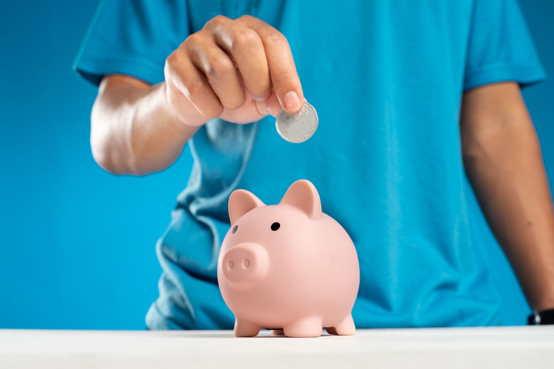 Child putting coins into a piggy bank, learning about kids accounts and saving money