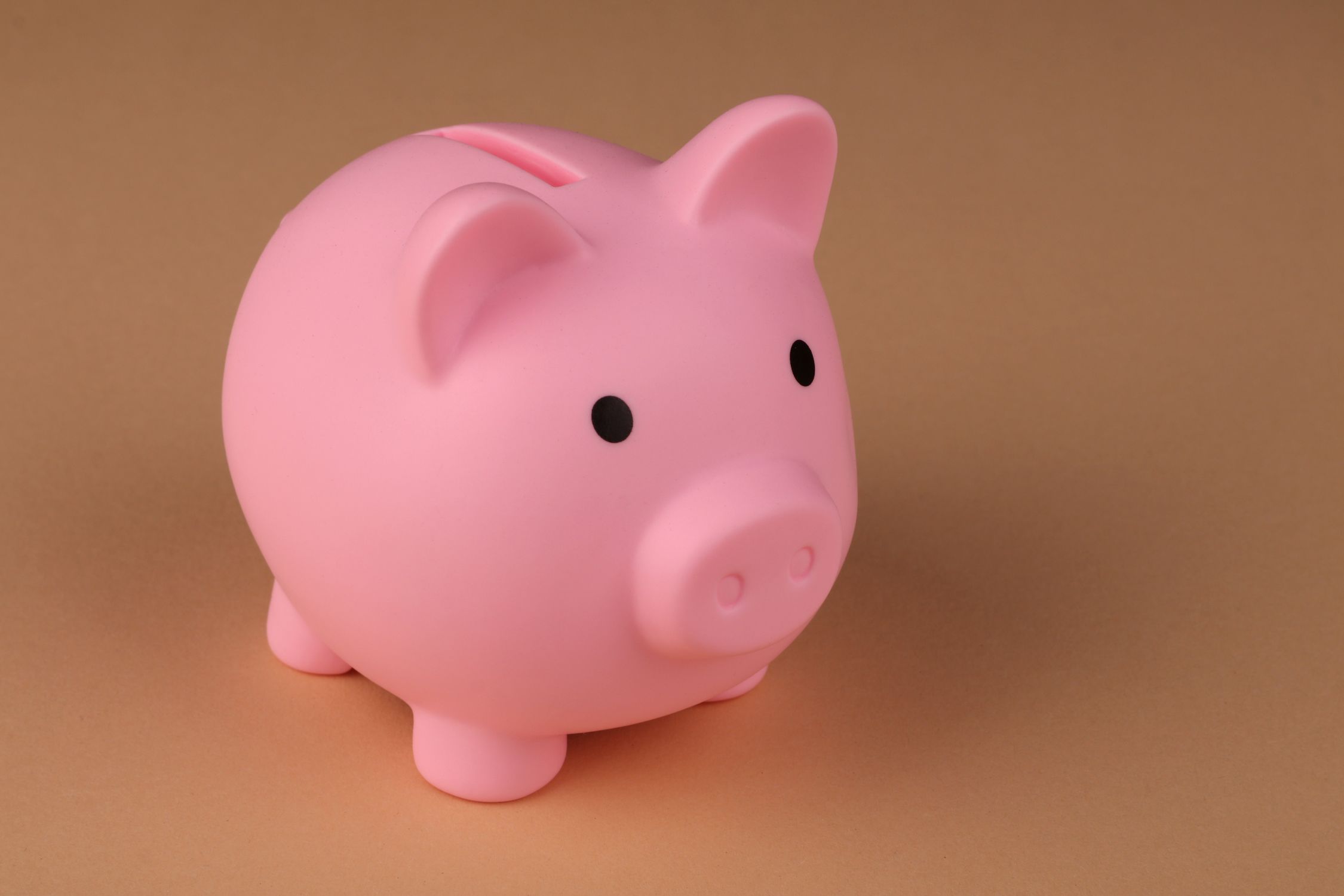 Child placing coin into piggy bank, learning about savings and bank accounts
