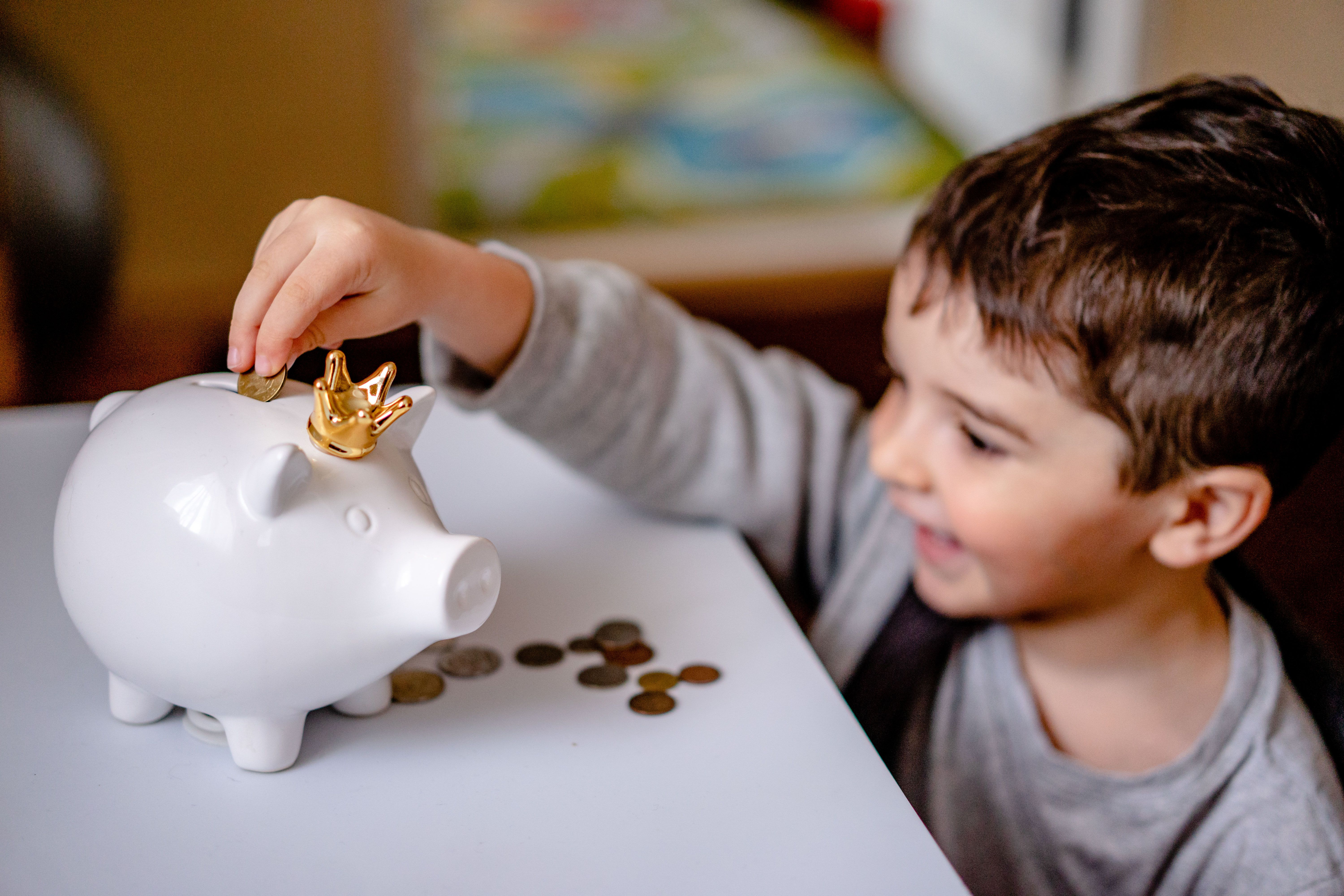 Boy putting coins into a piggy bank, representing kids learning to manage money