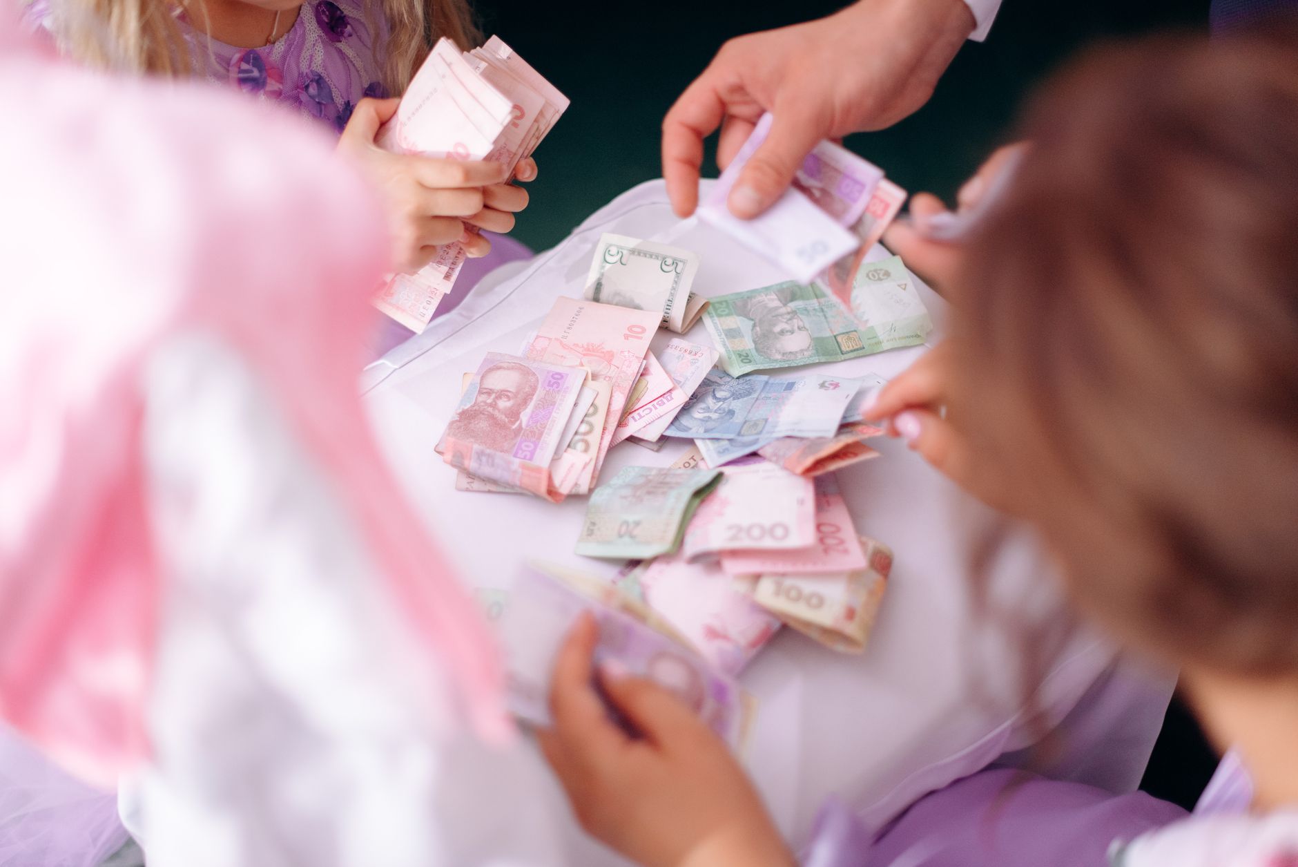 A child and adult sorting colorful banknotes together, learning money activities for 10 year olds