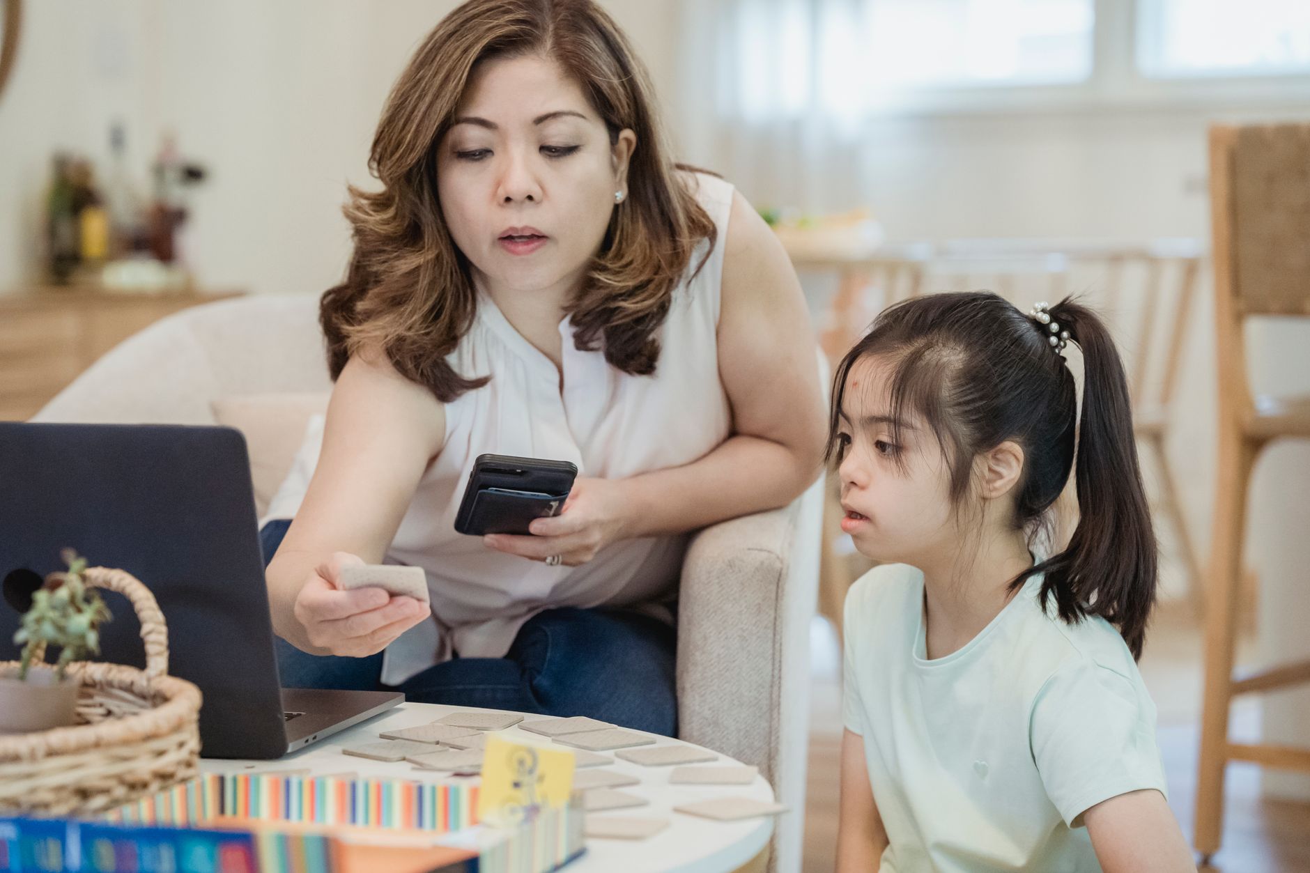 Parent sitting with a 7 year old child at a table, counting coins and learning about money together