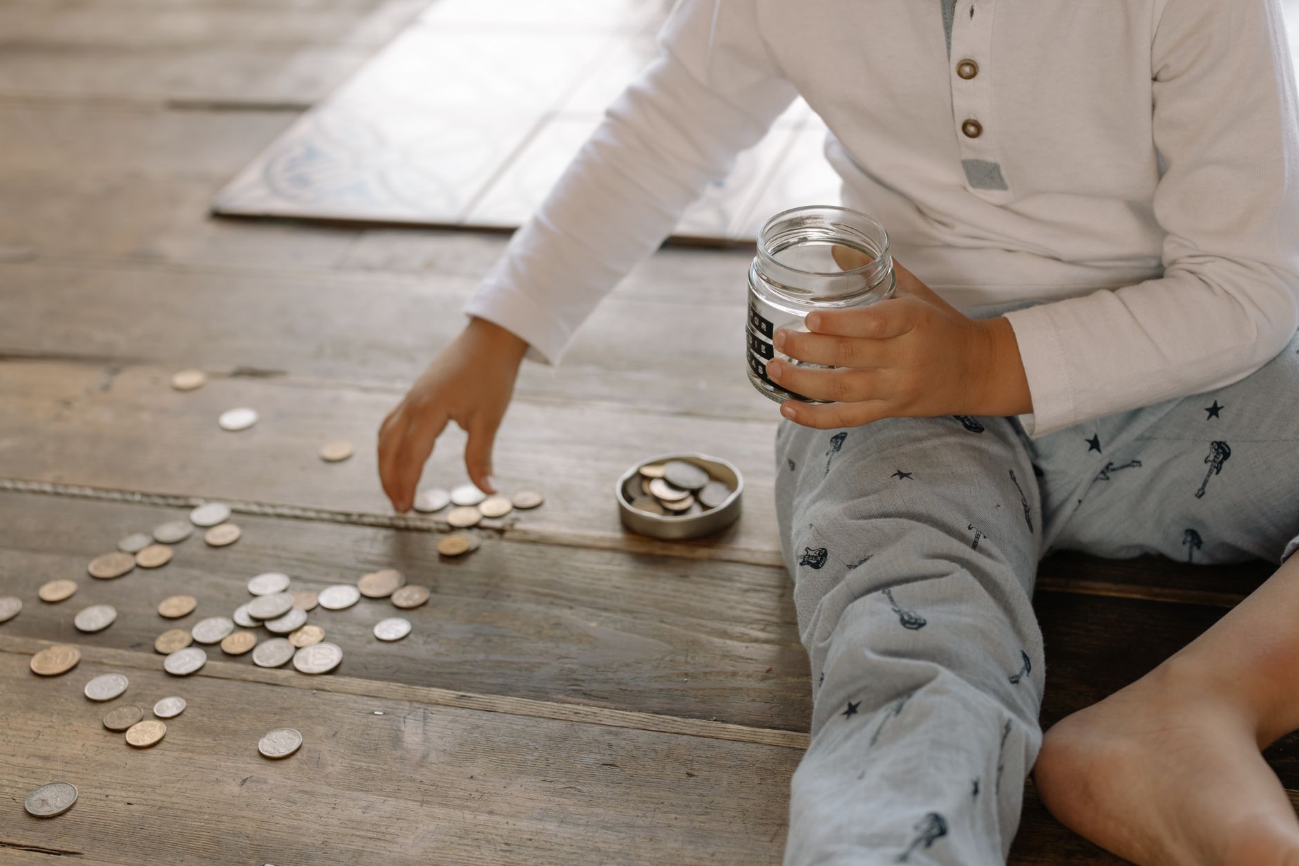 Child collecting coins into a savings jar to learn about money