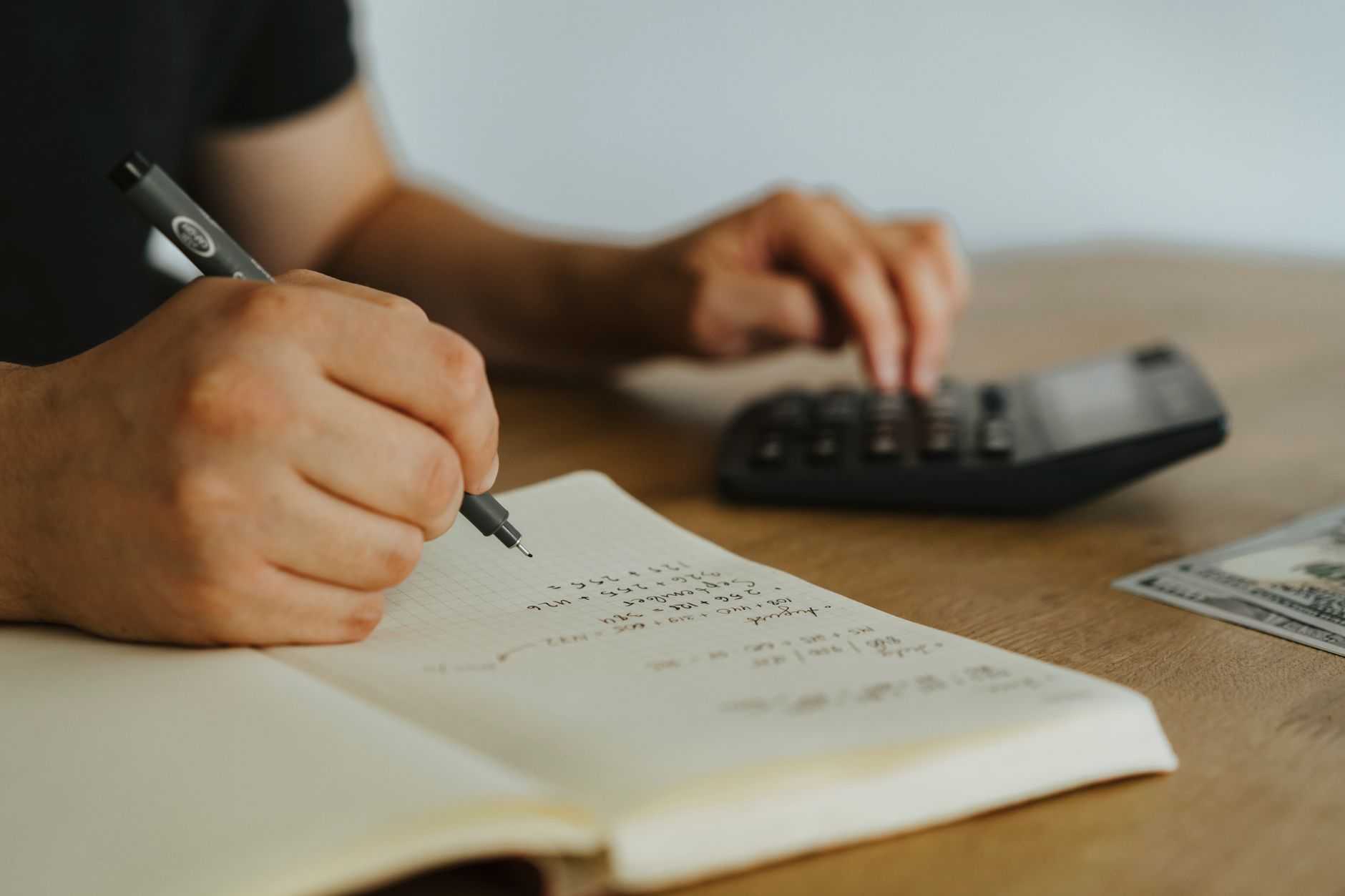 Teen writing in a money management workbook with calculator and notes