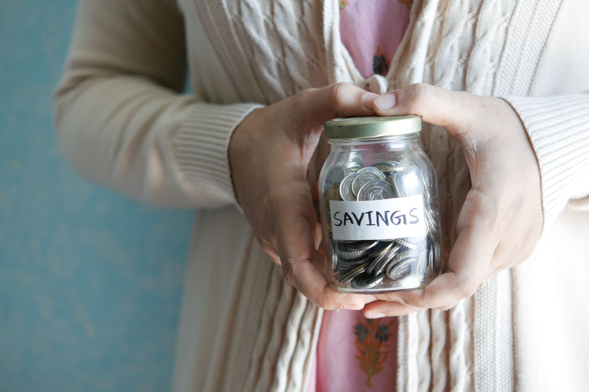 Child putting coins into a savings jar, learning about savings accounts for kids